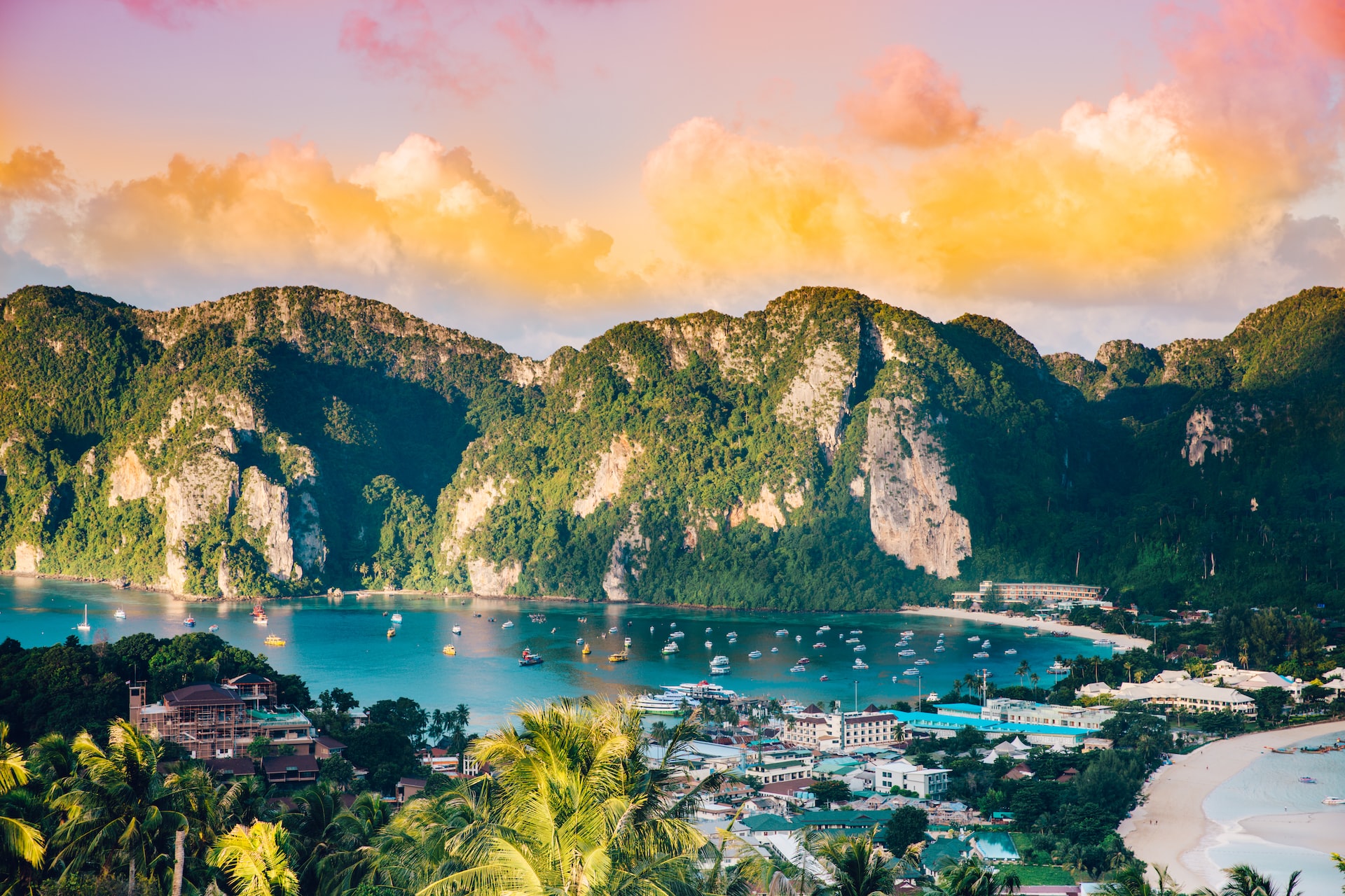 An image of a bay in Thailand, with boats floating in the water and mountains in the background.