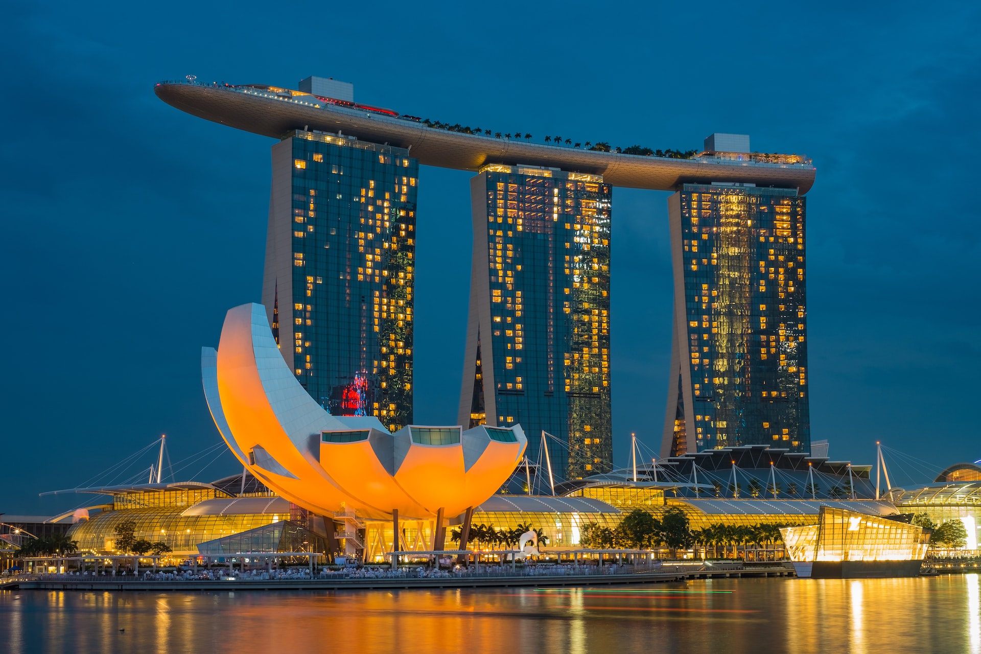 An image of the famous Marina Bay Sands hotel in Singapore at night. Three tall towers stand with a flat structure sitting across the top of them; it is often thought to look like a ship.