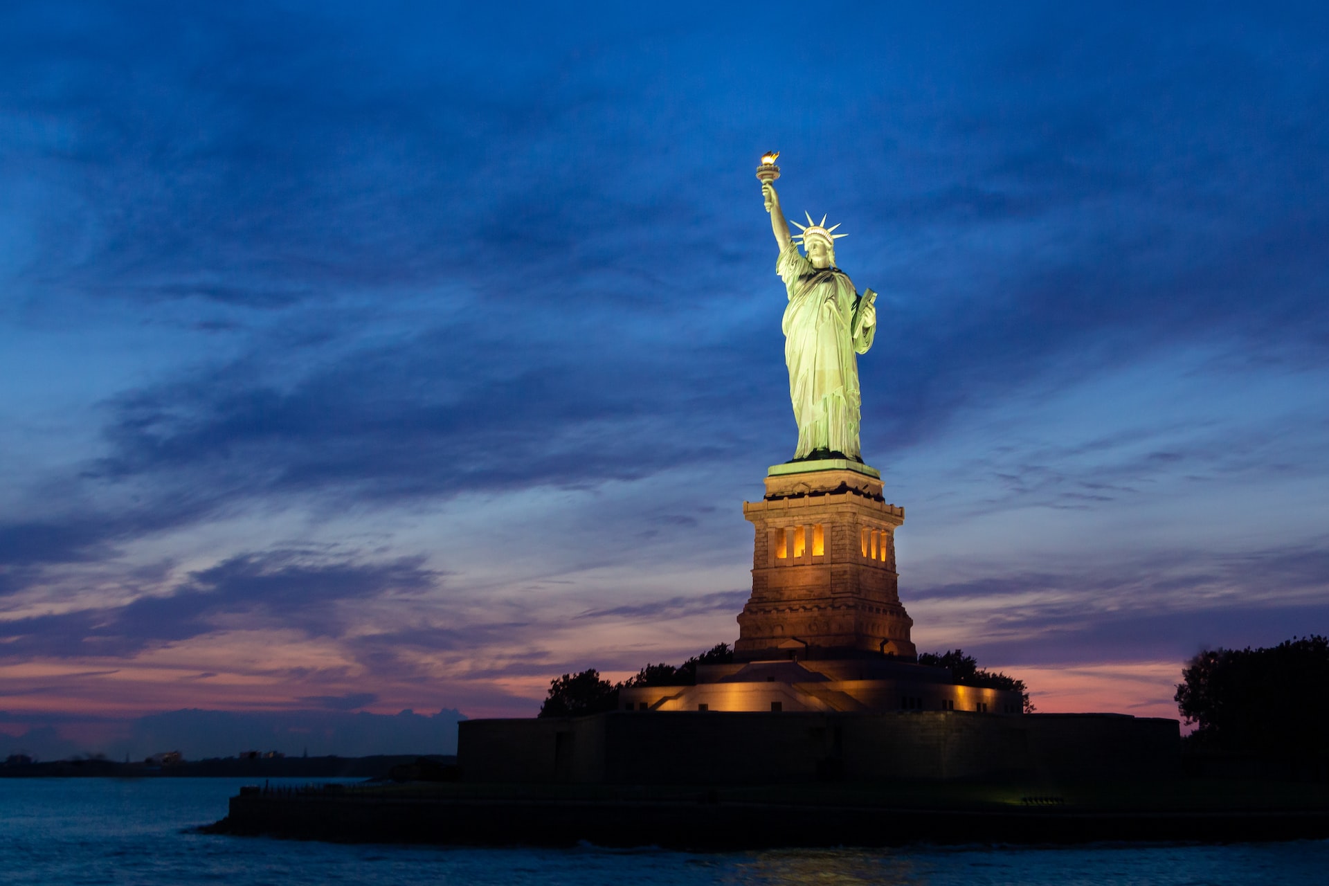 The Statue of Liberty, lit up at night.
