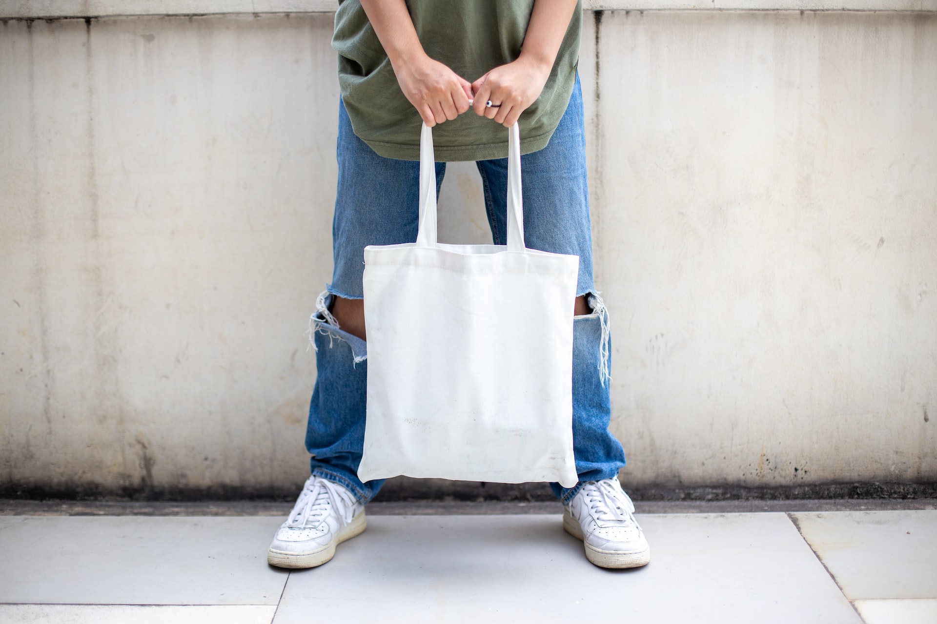 A man holds a white tote bag.