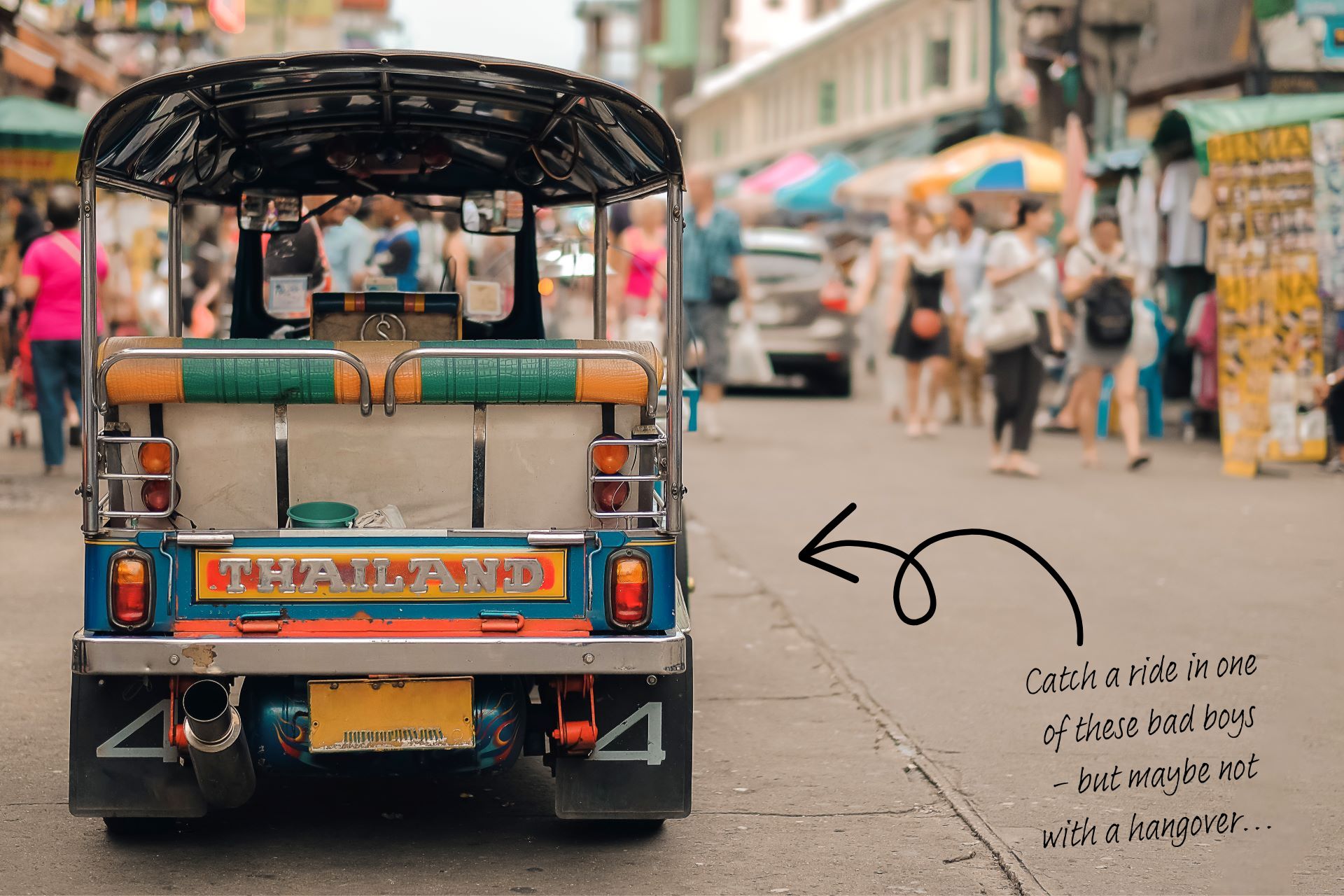 The back of a Tuk Tuk, parked on a street in Bangkok with people passing by. Handwritten font with an arrow pointing to the Tuk Tuk says "catch a ride in one of these bad boys - but maybe not with a hangover..."