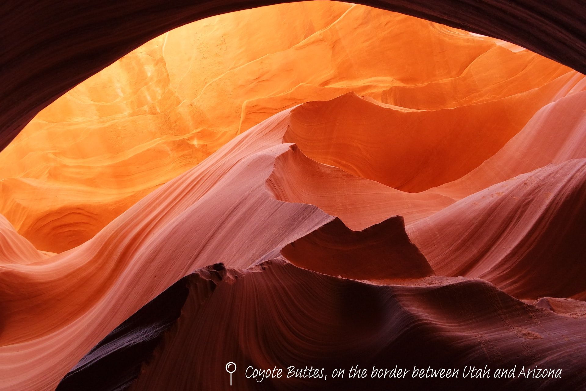 Rock formations curve like waves, turned orange by the sunlight.