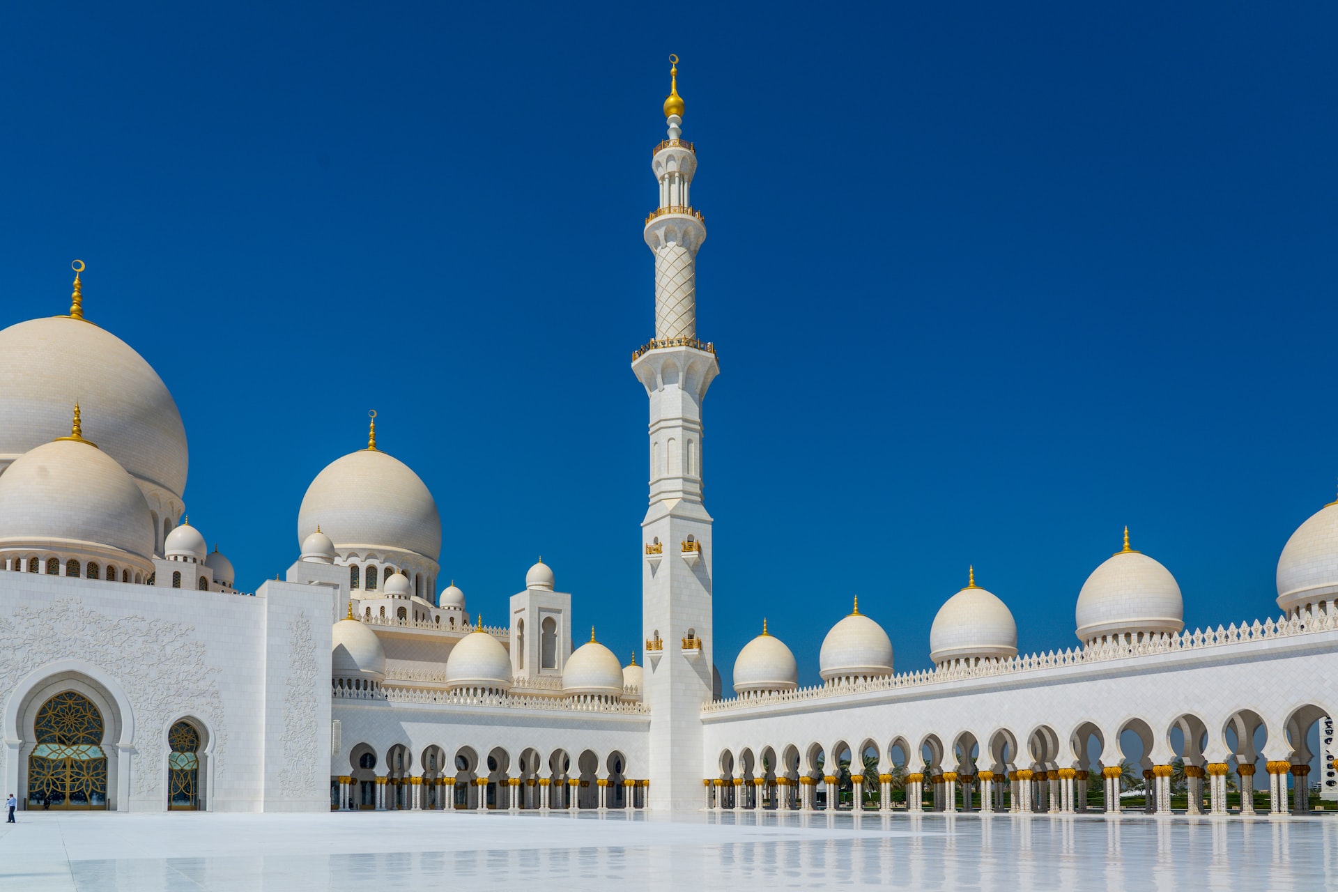 Sheikh Zayed Grand Mosque in Abu Dhabi, white cupolas and minarets against a bright blue sky.
