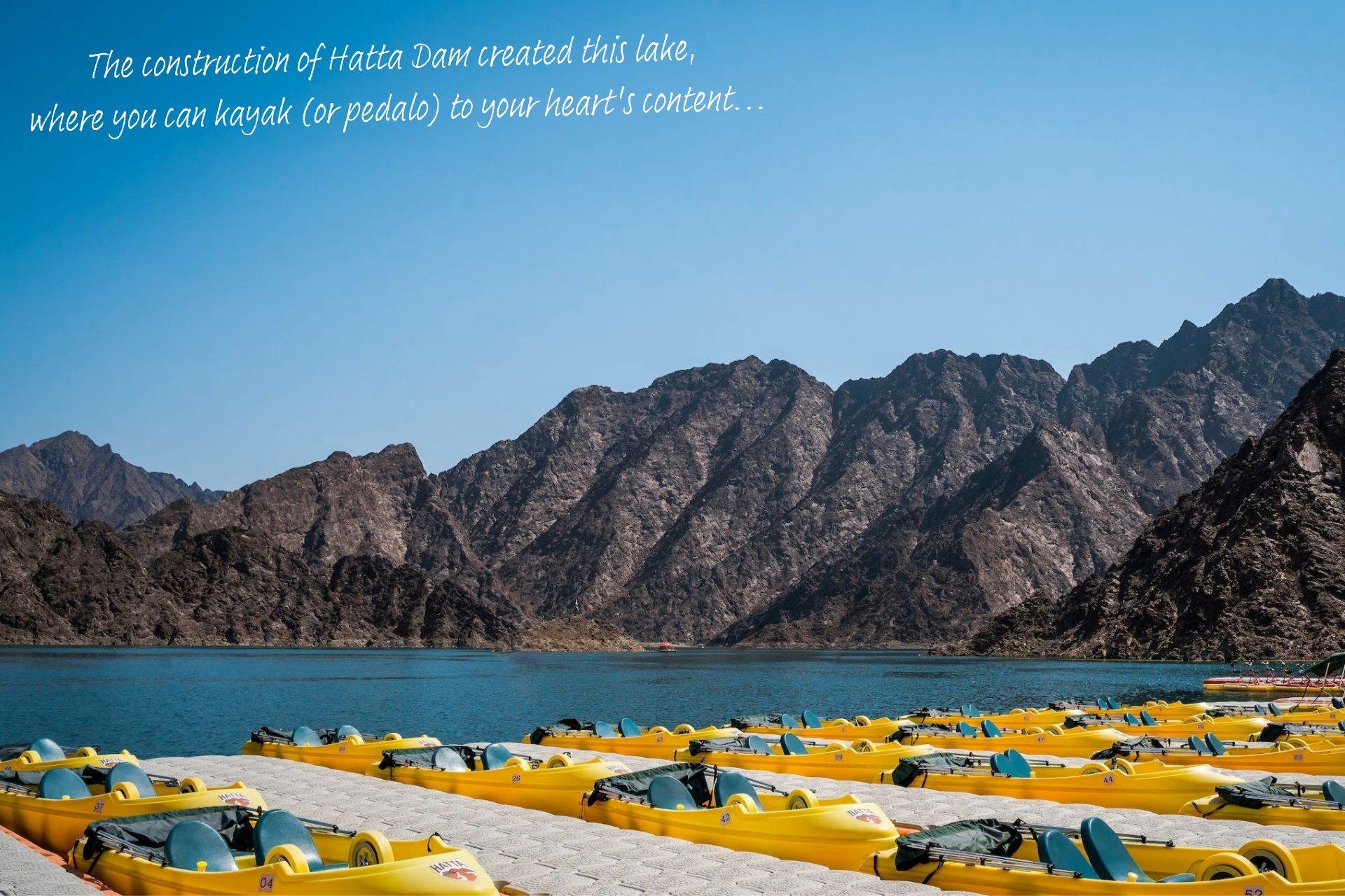 Hatta Lake, with a bank of pedalos in the foreground and the Hajar Mountains in the distance.