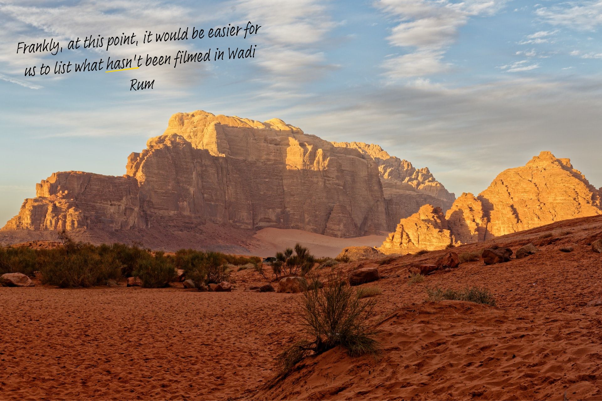 Wadi Rum in Jordan. A large rock formation reaches into the sky in the distance.