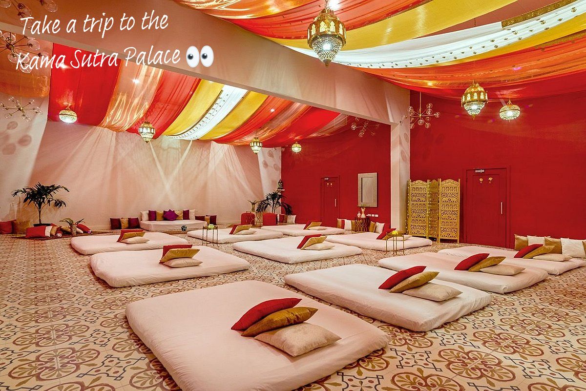 The Kama Sutra Palace at Hedonism II in Jamaica. A large room with beds on the floor, lots of warm red tones and soft lighting.