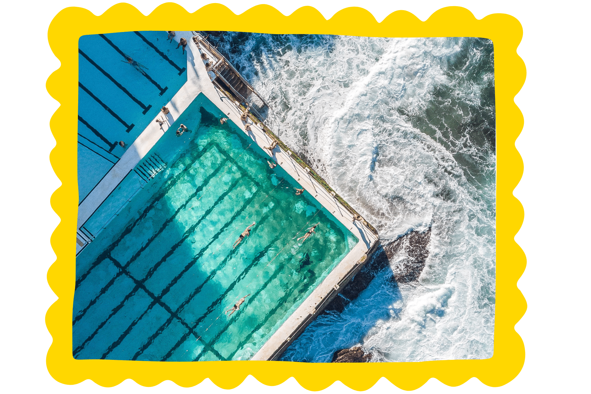 The swimming pool at Bondi Icebergs as seen from above. Waves crash around the pool, protected by its barriers.