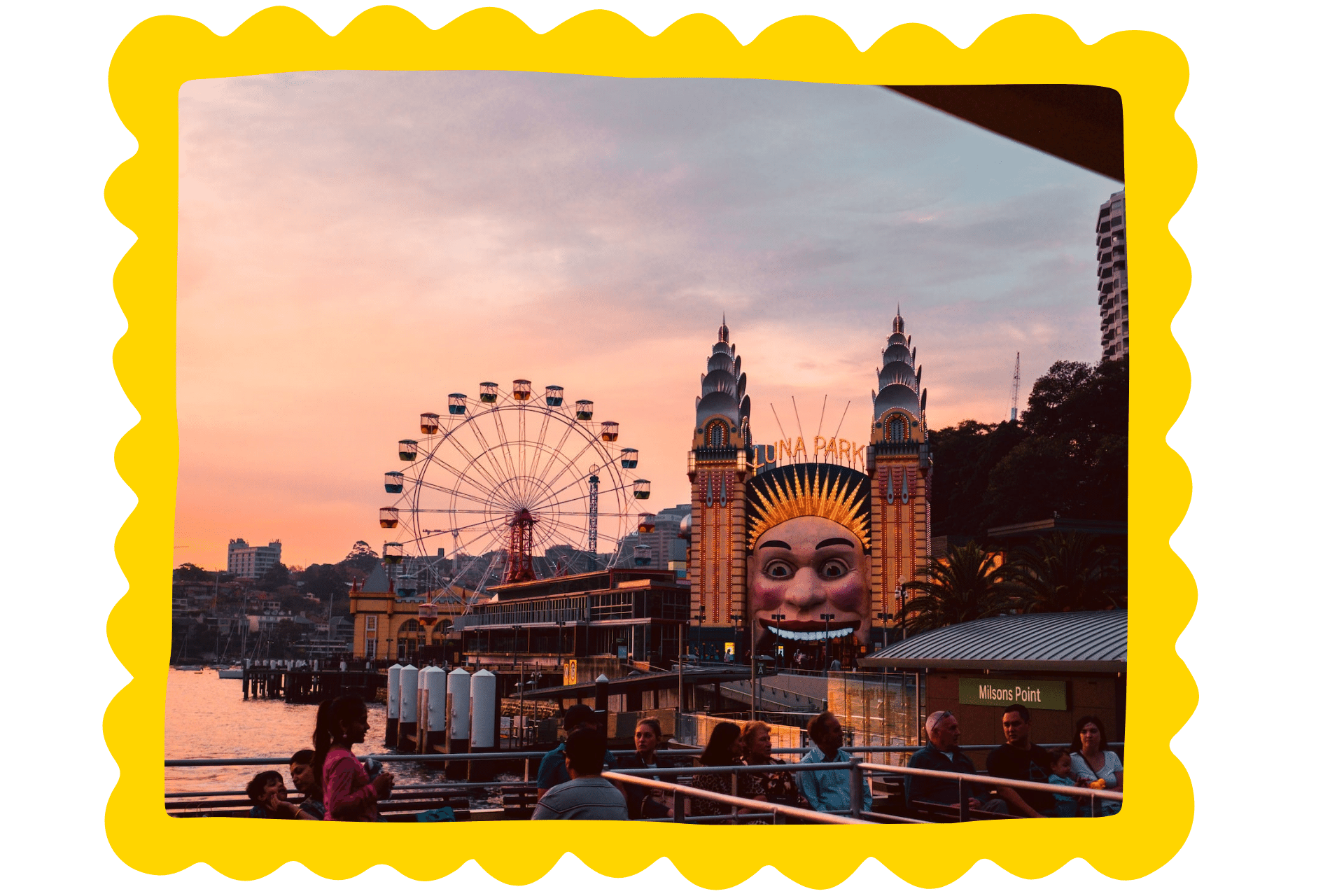 A fairground at sunset, with illuminations and a Ferris wheel.