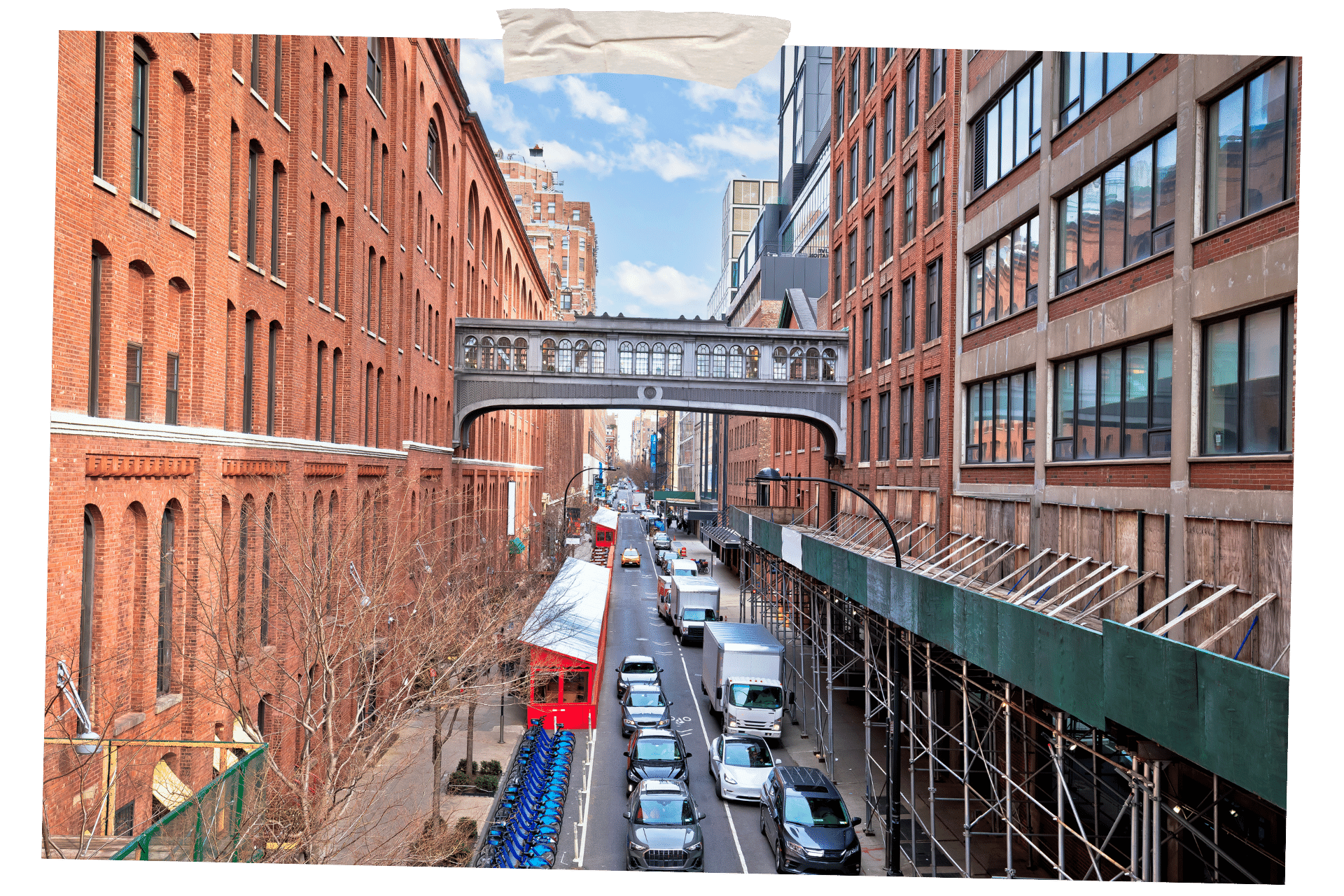 When it comes to New York for Foodies, you have to visit a food market. Pictured is a street in New York, building either side and a bridge connecting the two. On the ground floor level is the entrance to Chelsea Market.