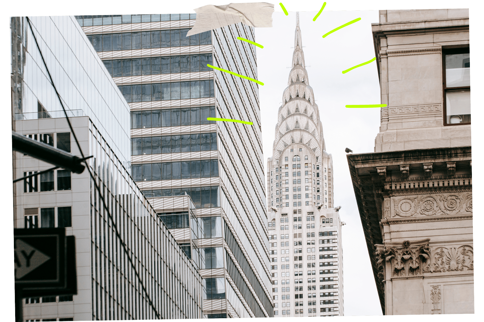The Chrysler Building is one of the must-visit historic sites in NYC. Image shows the top of the Chrysler Building between surrounding skyscrapers, with it's tapered end and triangle windows reaching into an overcast sky,