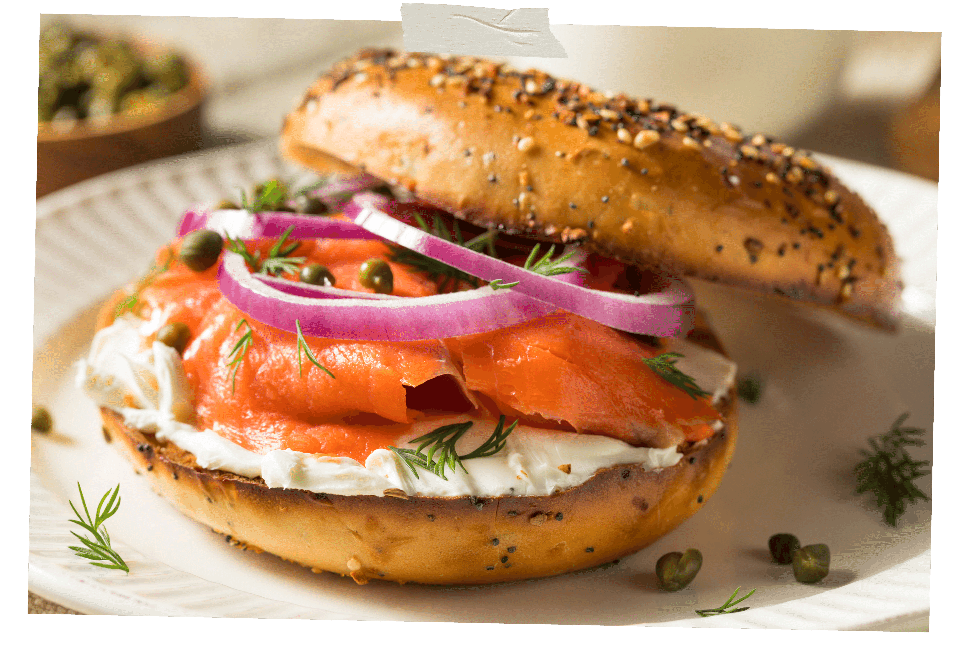 When it comes to New York for Foodies, a cream cheese bagel is a classic. Pictured is a bagel on a white plate, half open to reveal it's contents: cream cheese, salmon, and onions.