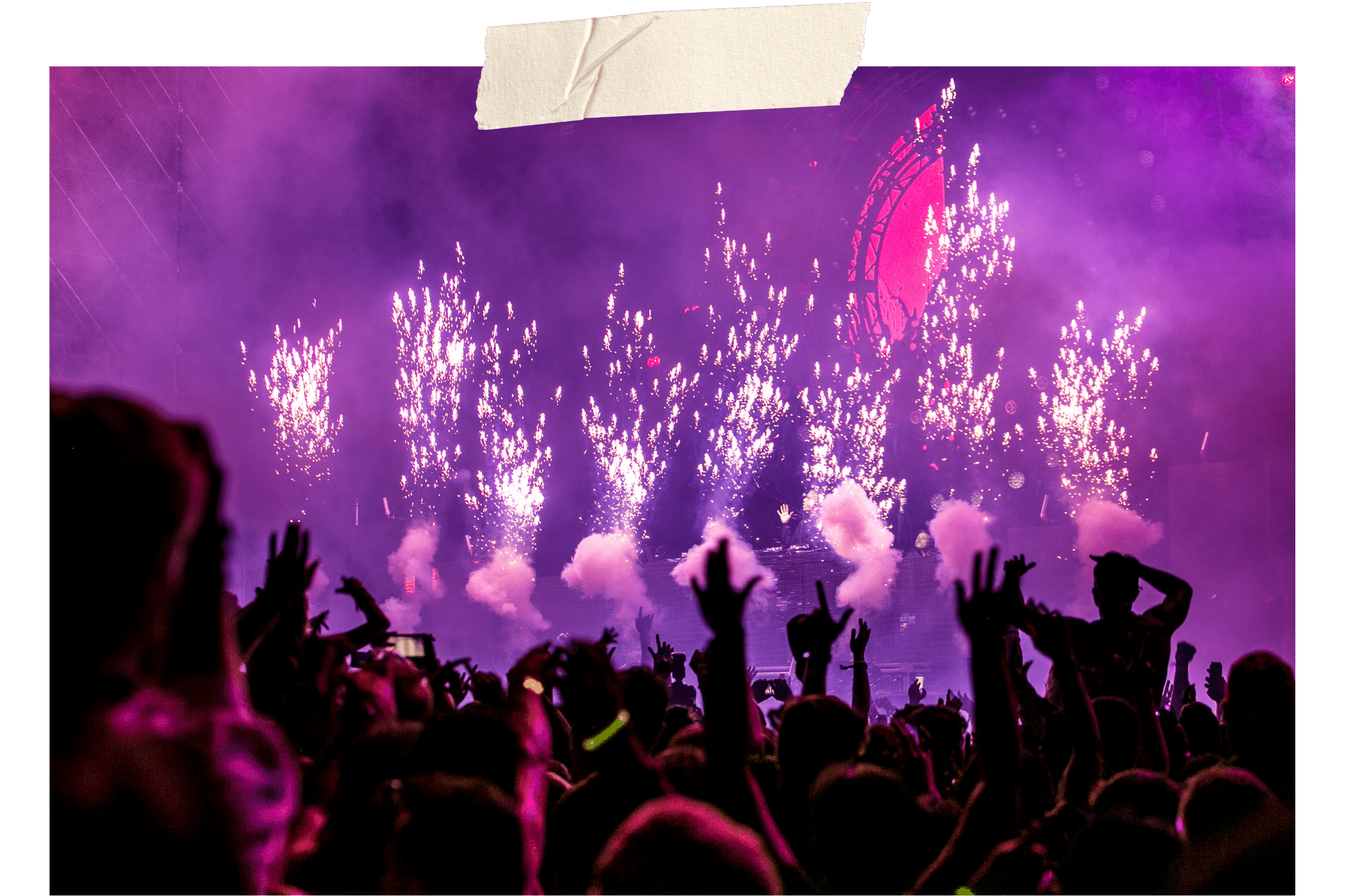 Image shows the interior of a night club, lit in pruple with hands in the air, sparks, and smoke effects.