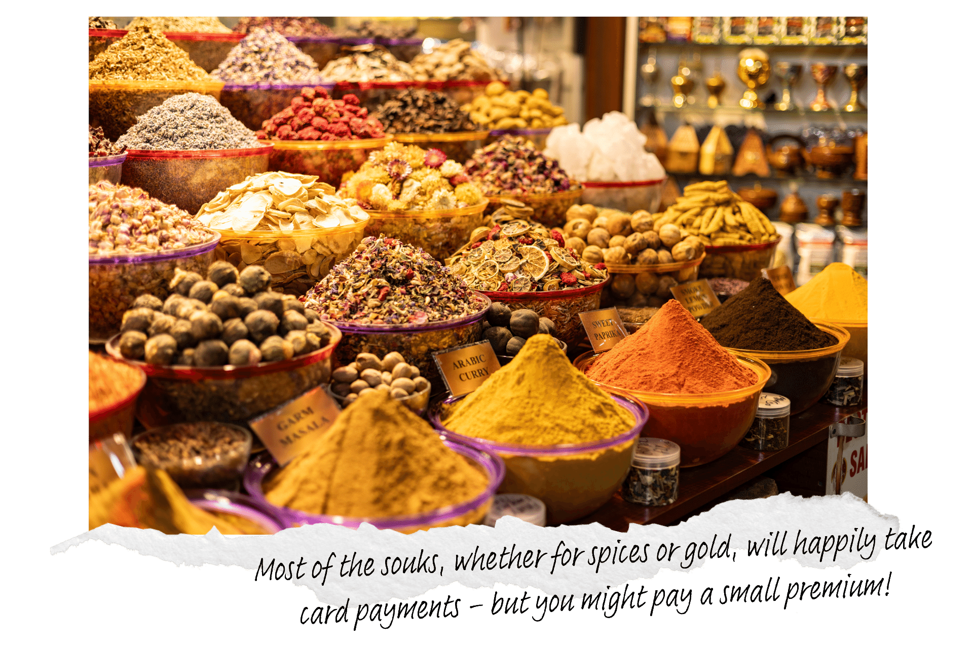 When it comes to Dubai for first timers, know where you can use your card or need cash. Image shows a traditional spice souk in Dubai, with a close up shot of bowls of various spices piled high into a conical shape.